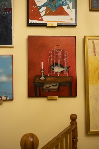 Obraz przedstawiający klatkę z rybą w środku, stojące na biurku